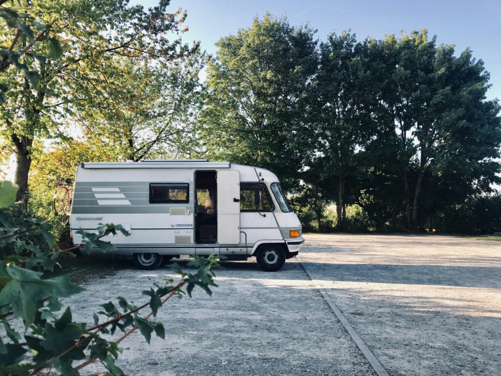 RV in a parking surrounded by lush greenery